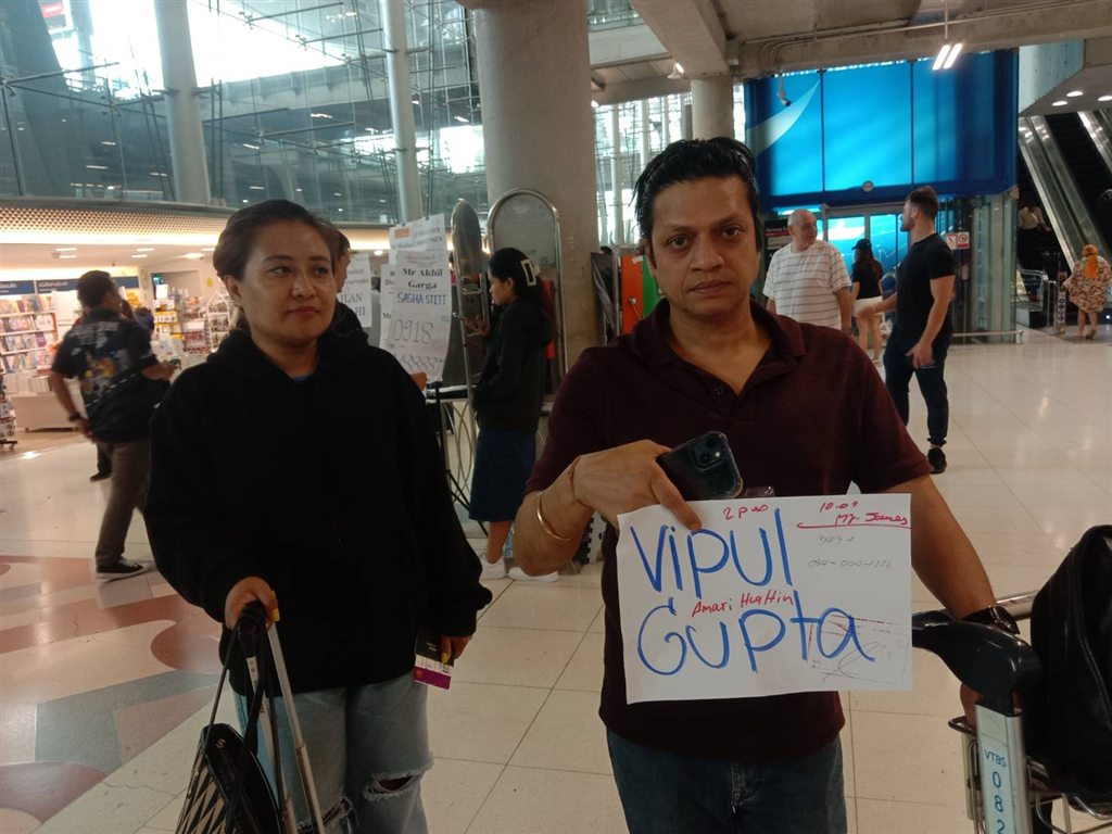 A customer holds up his name sign in the airport arrivals hall