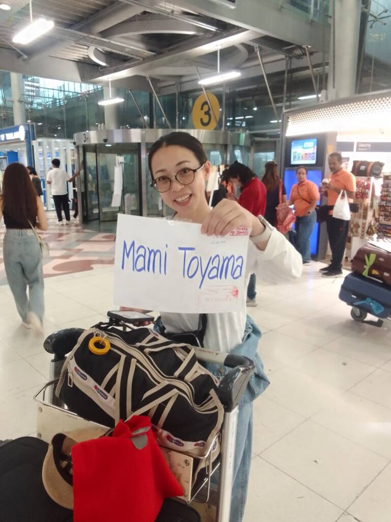 A smiling customer holds a sign with her name at arrivals